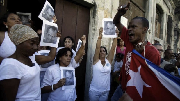 A Castro goon harassing a group of Ladies in White holding posters of the former political prisoner Orlando Zapata Tamayo who died in prison on a hunger strike.