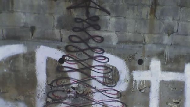 Graffiti of a tall Christmas tree painted over the initials of the Committee for Defense of the Revolution