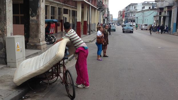A man places a mattress on a bicycle in a street of Havana. (14ymedio)