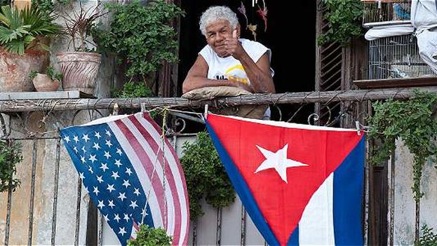 The flags of Cuba and the United States waving as a lady on her balcony gives the “thumbs up.” (EFE)