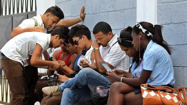 A group of young people connect to the internet in a wifi zone in Havana. (EFE)